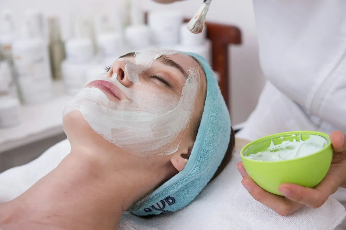A therapist applies a cream mask during a basic facial