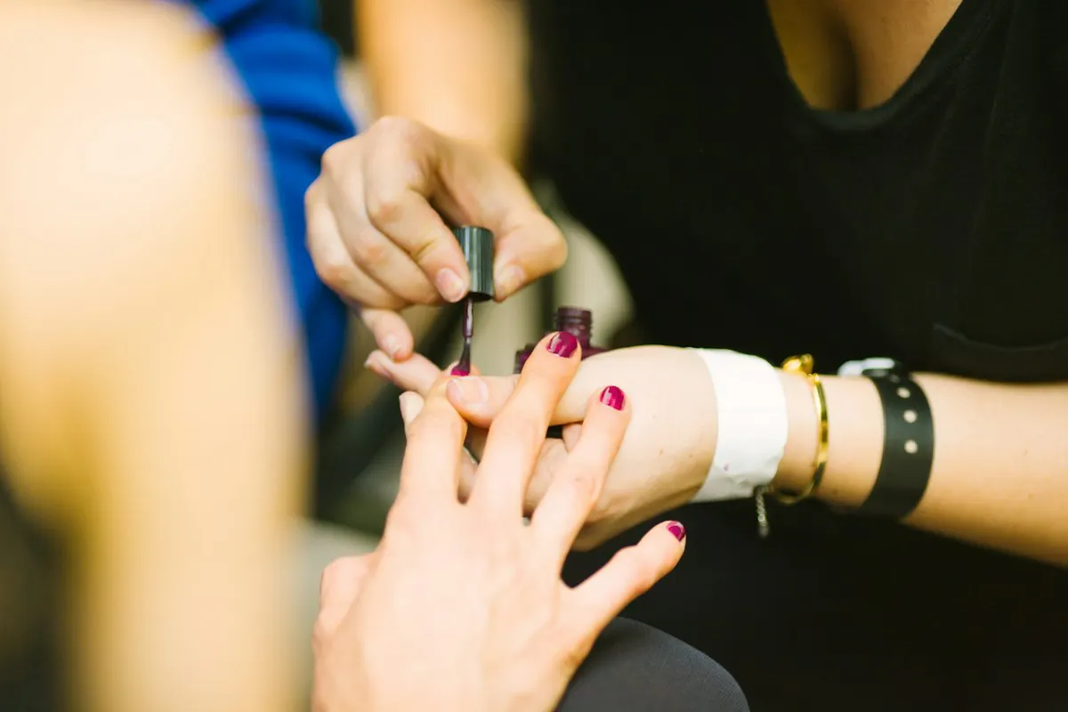 A manicurist tidies a guest's nails during a manicure